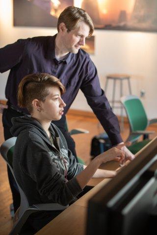 Teacher helping student with graphic art on tablet